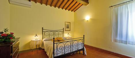 Un dormitorio con cama, lámparas de noche, cómoda y ventana con cortinas.