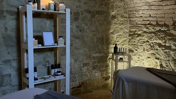 Experience a traditional retreat with a rustic stone wall, shelving unit, and simple bed.