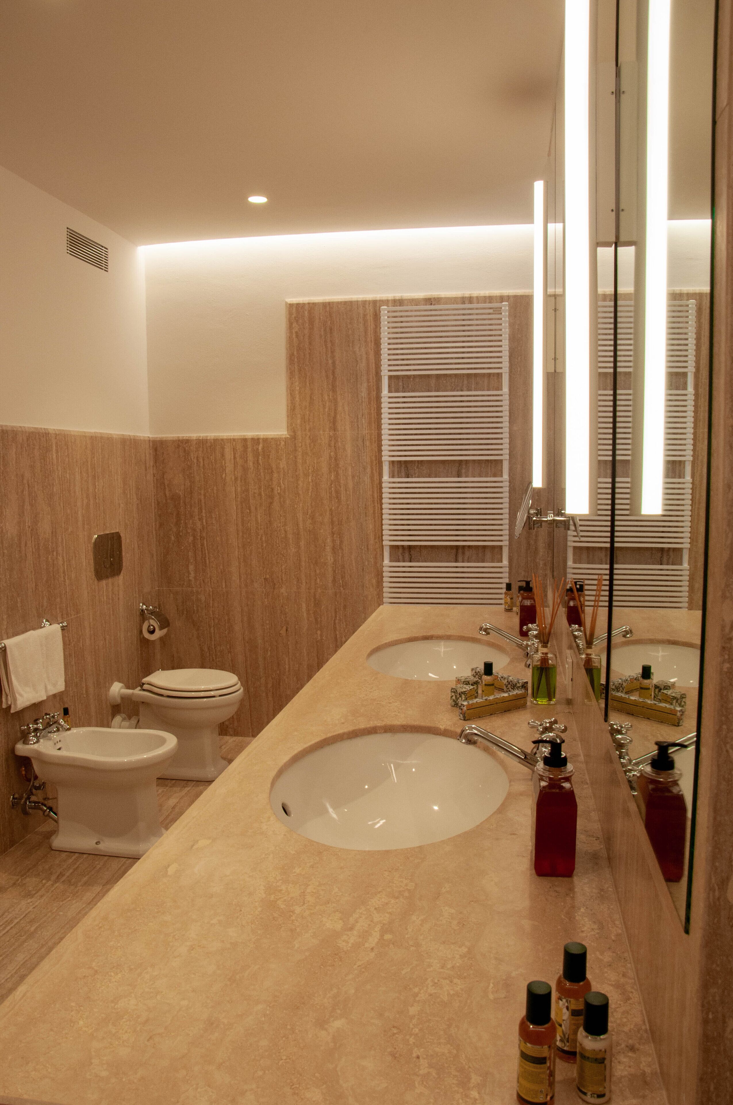 A modern bathroom with two sinks, a toilet, and a bidet.