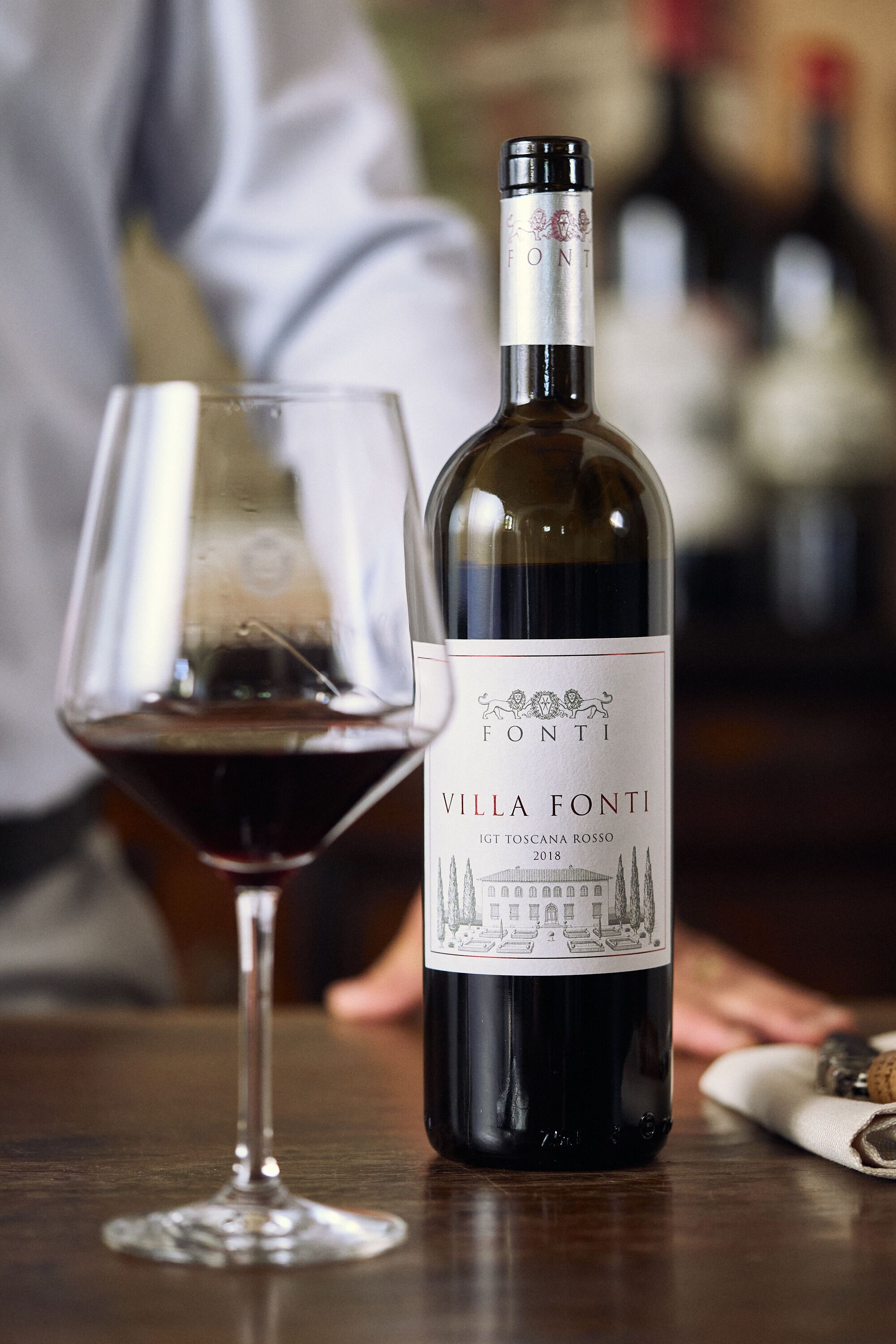 A bottle of wine and a glass on a wooden table.