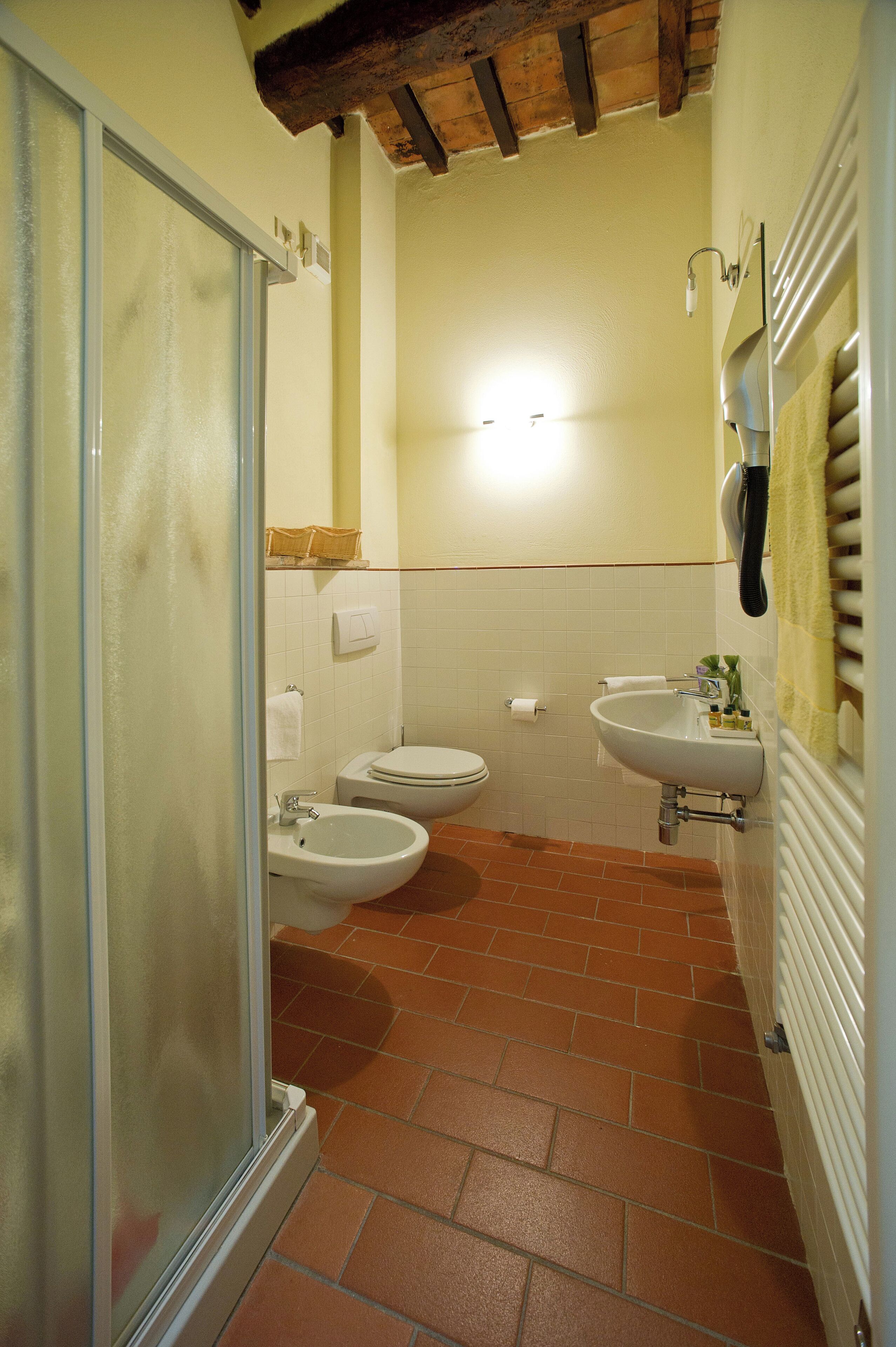 A bathroom with a glass shower door, a toilet, a bidet, and a sink.
