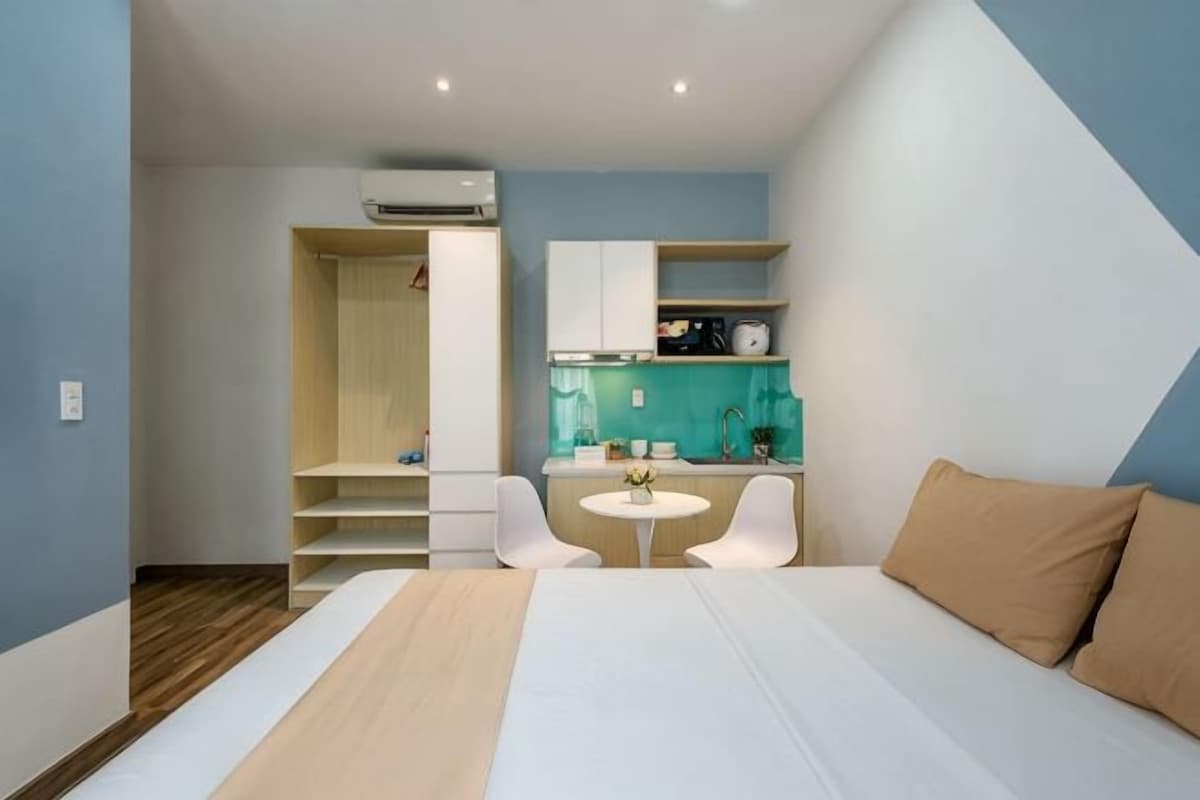 Una habitación de hotel moderna con cama, escritorio, silla, una mesita y un rincón americano.