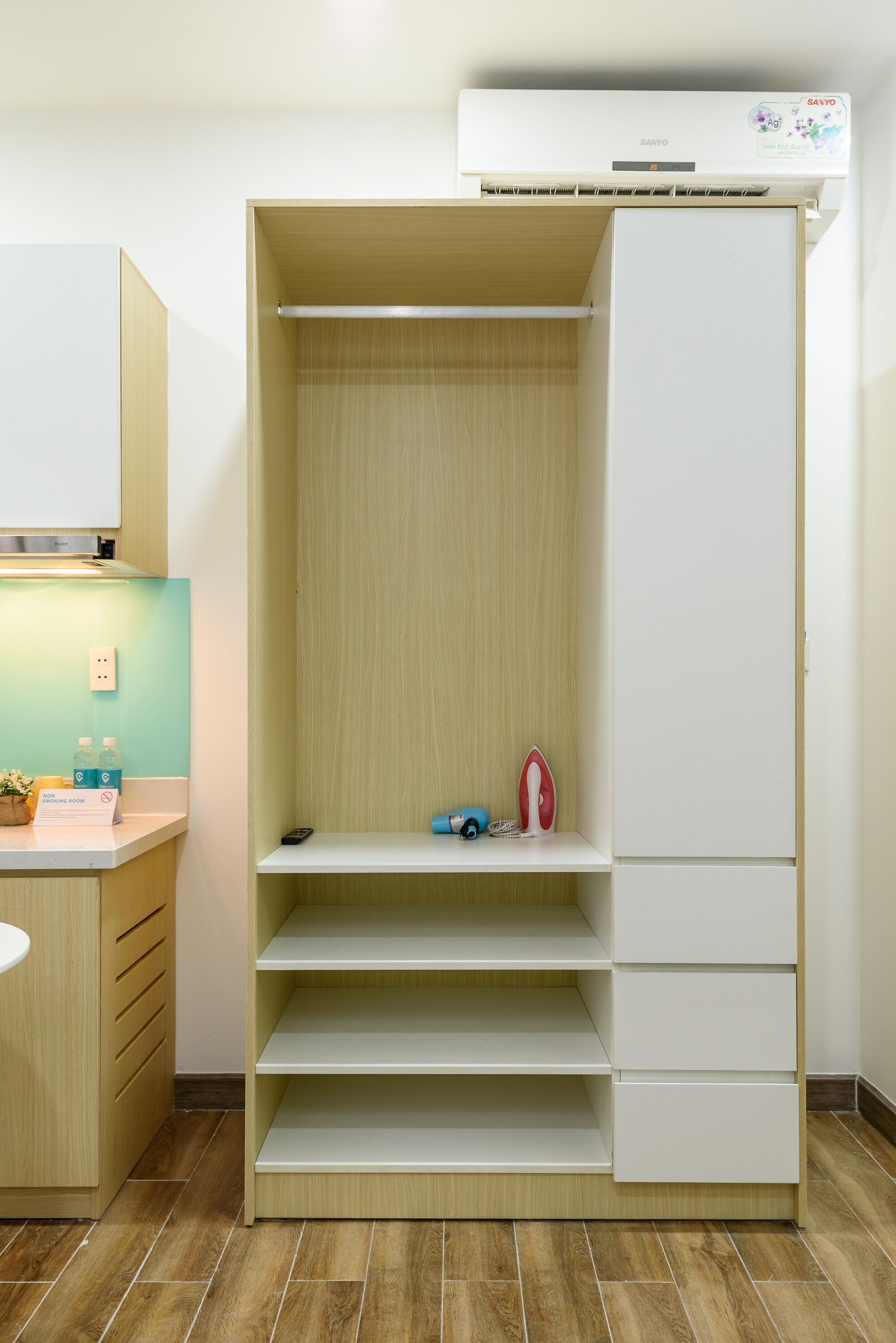 Habitación moderna y minimalista con armario empotrado, un escritorio pequeño con lámpara y estante con objetos personales.