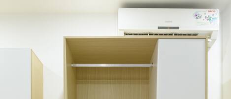 Habitación moderna y minimalista con armario empotrado, un escritorio pequeño con lámpara y estante con objetos personales.