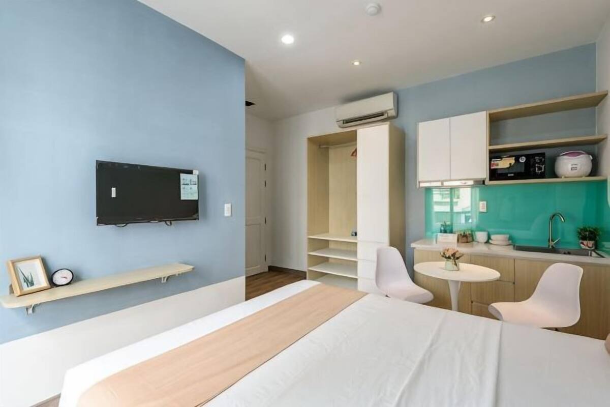 Habitación de hotel moderna con cama, televisor, pequeña cocina y baño.