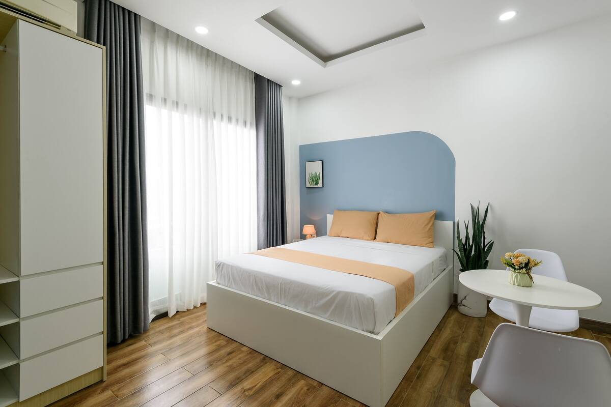 Una habitación de hotel moderna con una cama grande, una mesita de noche, una pequeña mesa redonda y un armario.