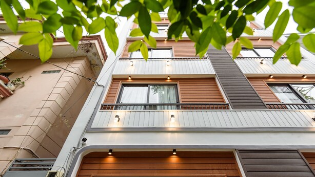 A multi-story residential building with balconies, windows, and a visible air conditioning unit. - Cozrum Homes - Summer's House (Ho Chi Minh City)