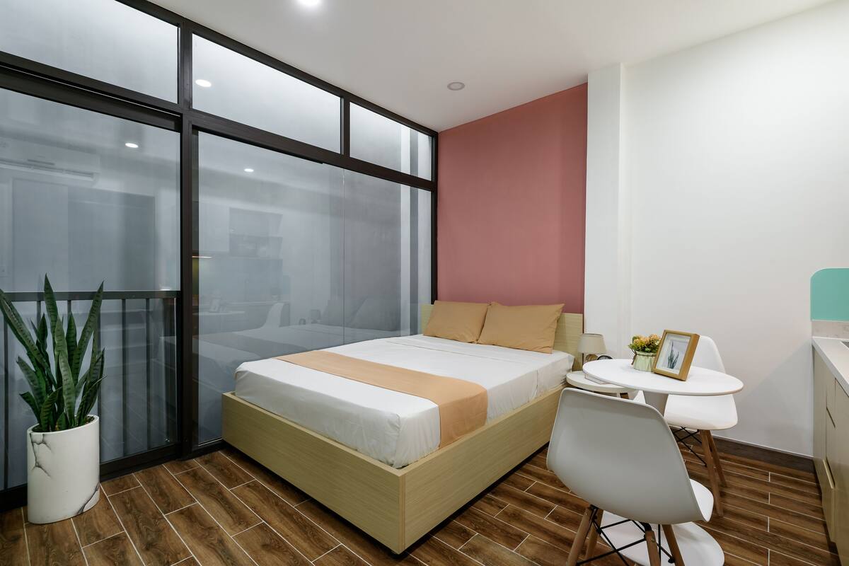 Un dormitorio moderno con cama, mesita de noche, silla y una planta en maceta.