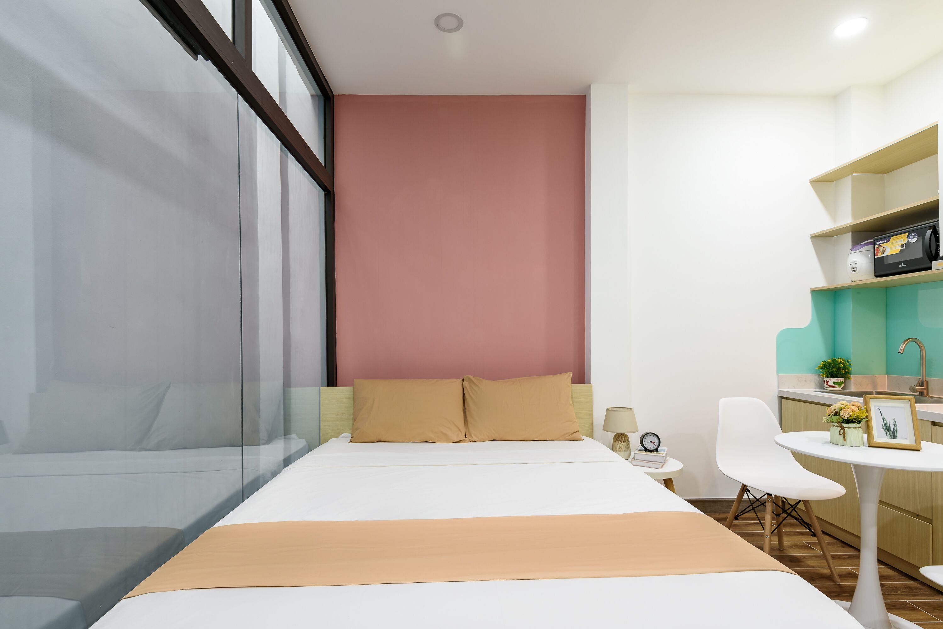 Una habitación de hotel moderna con una cama, una mesita con una silla, un escritorio con computadora y una ventana con persianas.