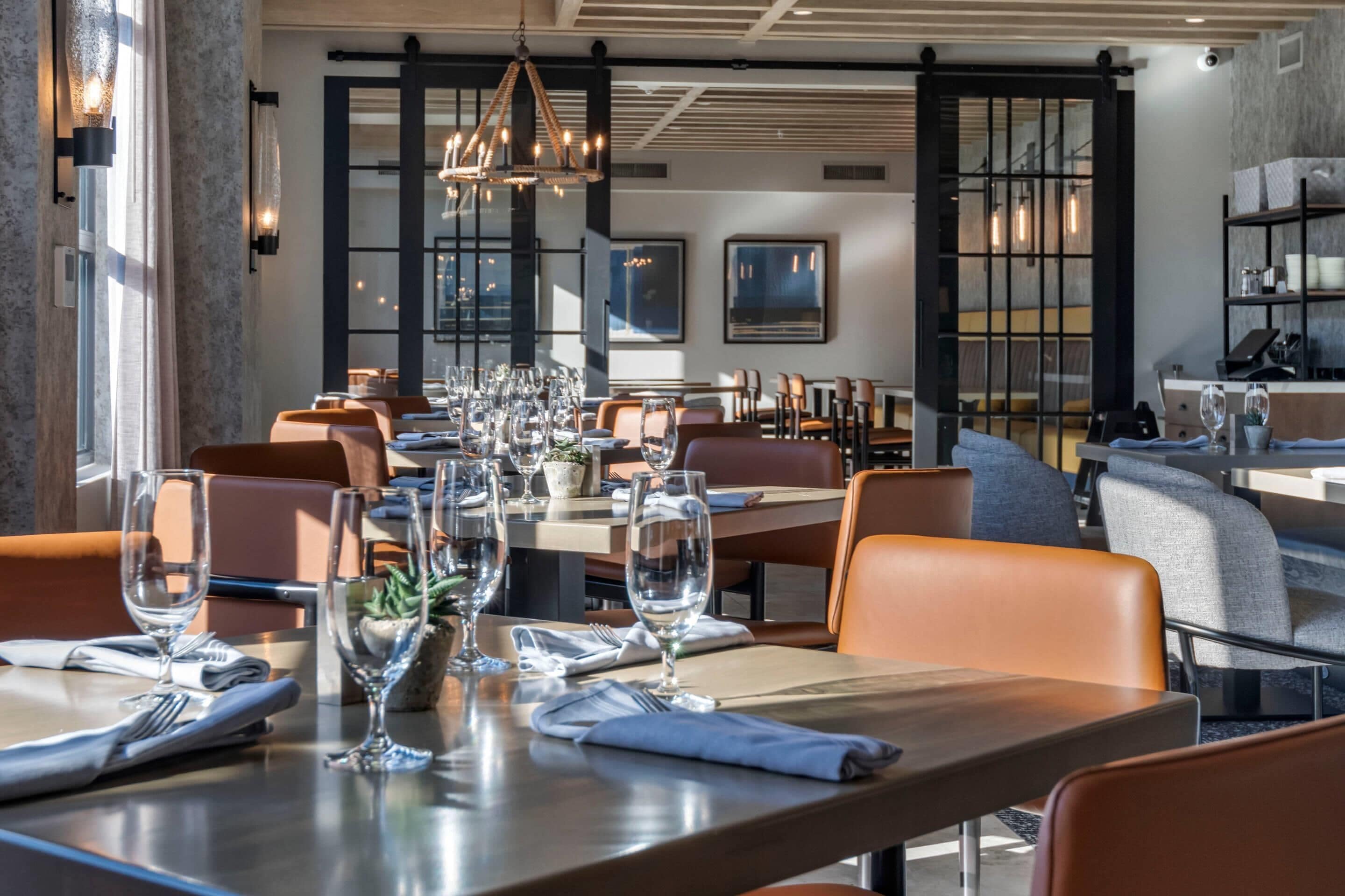 A modern restaurant with neatly arranged tables, chairs, and wine glasses.