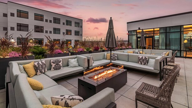 Una terraza en la azotea con un área de estar exterior moderna, un hogar para fuego y vistas de la ciudad.
