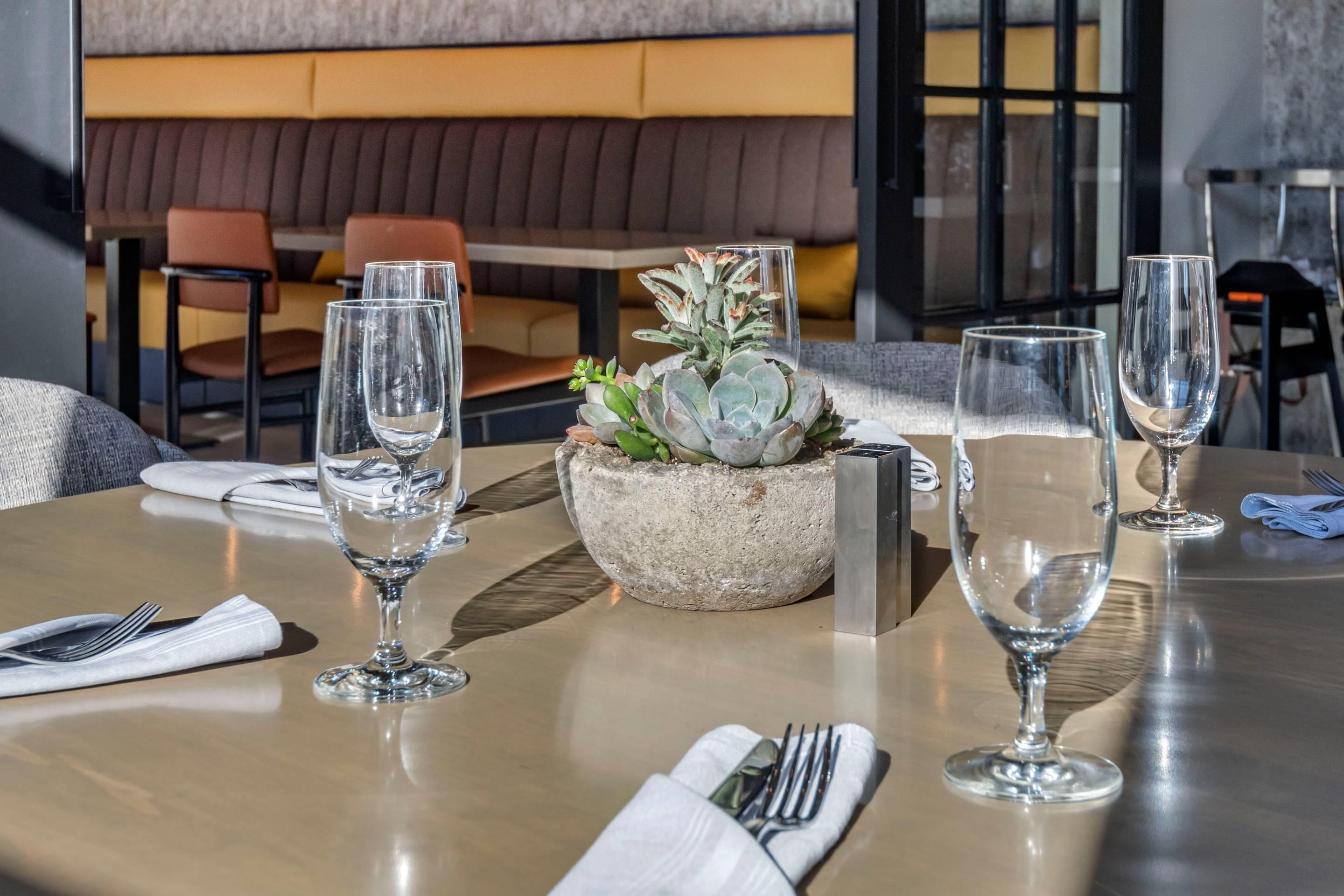 Ein gedeckter Restauranttisch mit Weingläsern, einer Tischdekoration und einer Servette.