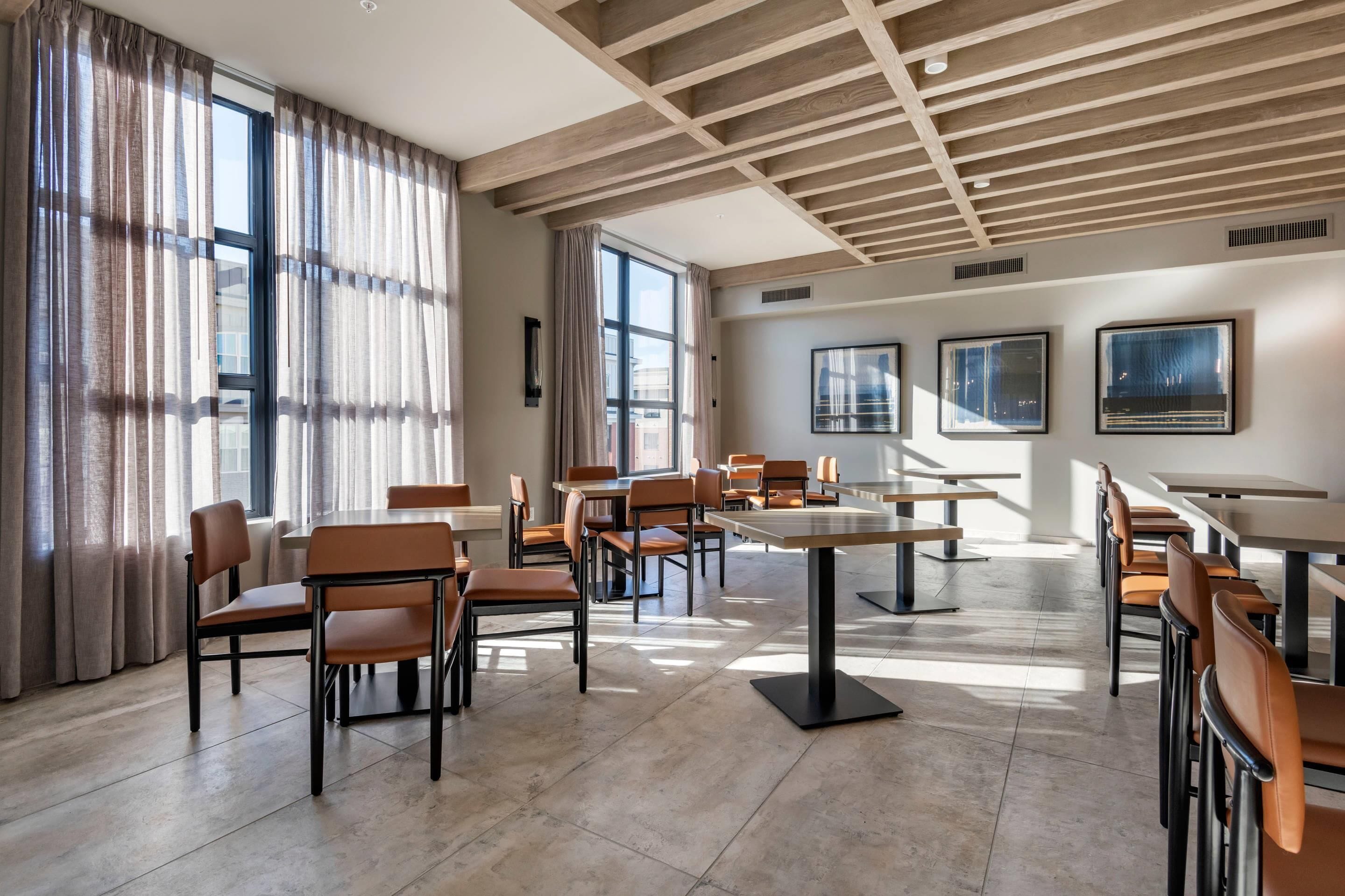 A spacious conference room with modern furniture, large windows, and a wooden ceiling.