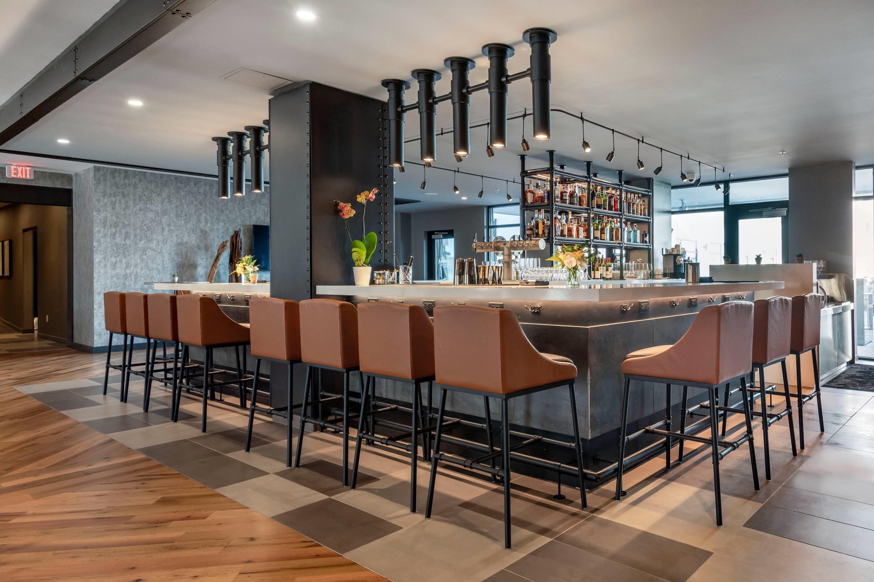 A modern bar area with a central island, bar stools, and a well-stocked liquor shelf.