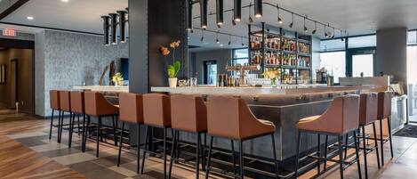 A modern bar area with a central island, bar stools, and a well-stocked liquor shelf.