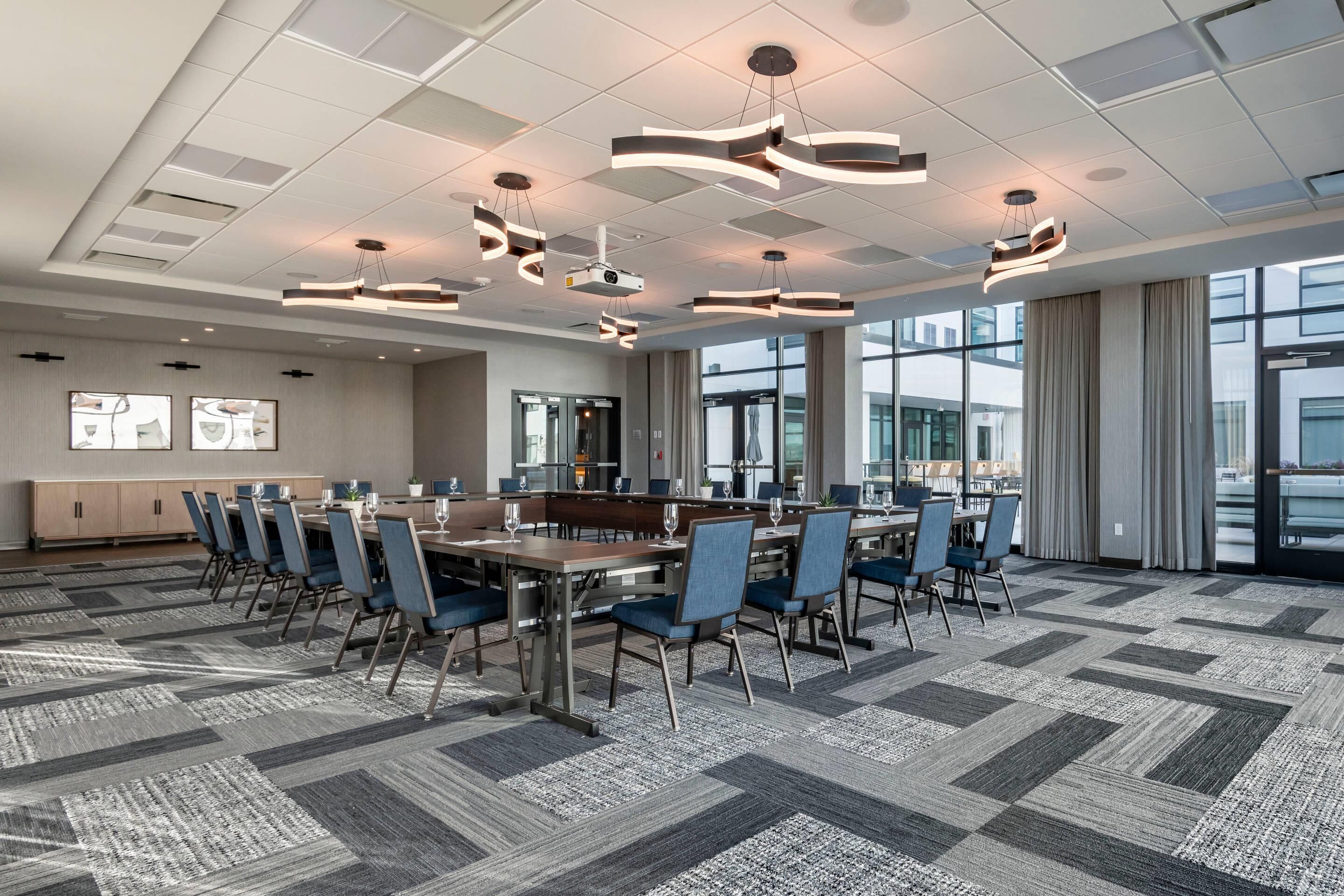 A conference room with a long table, blue chairs, and modern pendant lighting.