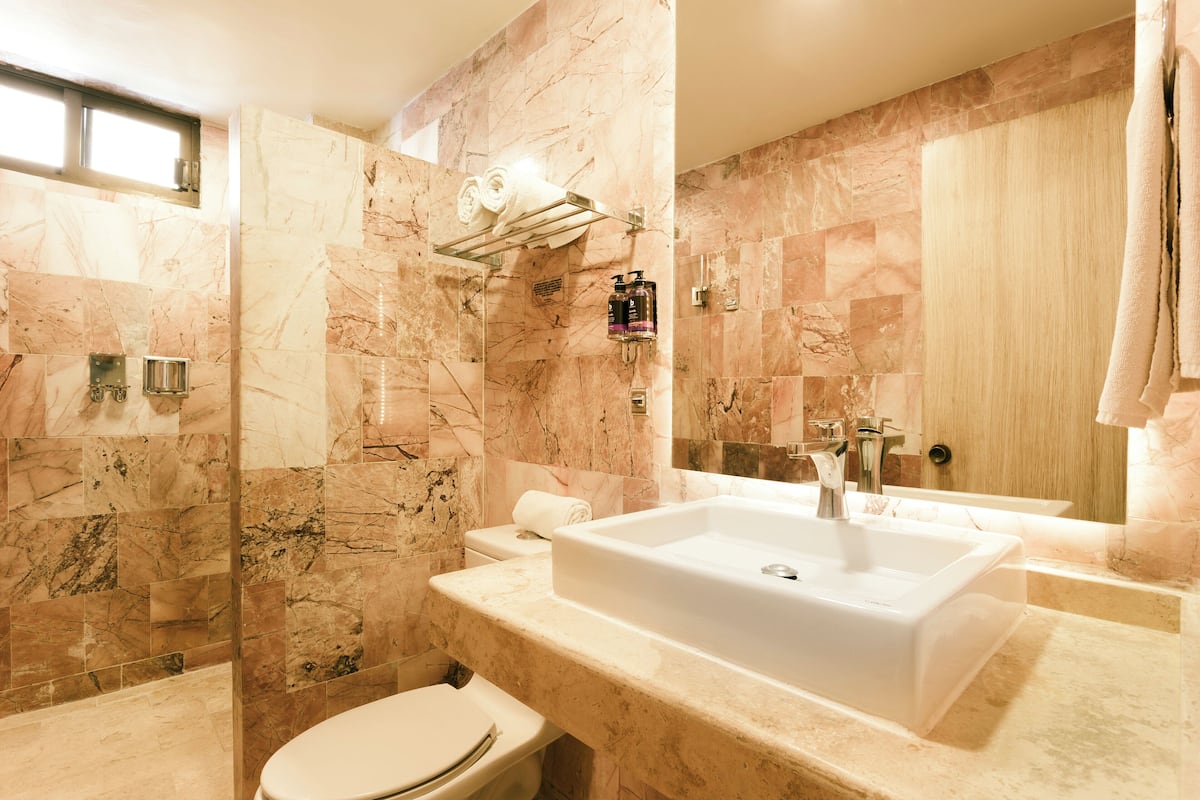 A modern bathroom with a large sink, toilet, and shower area.