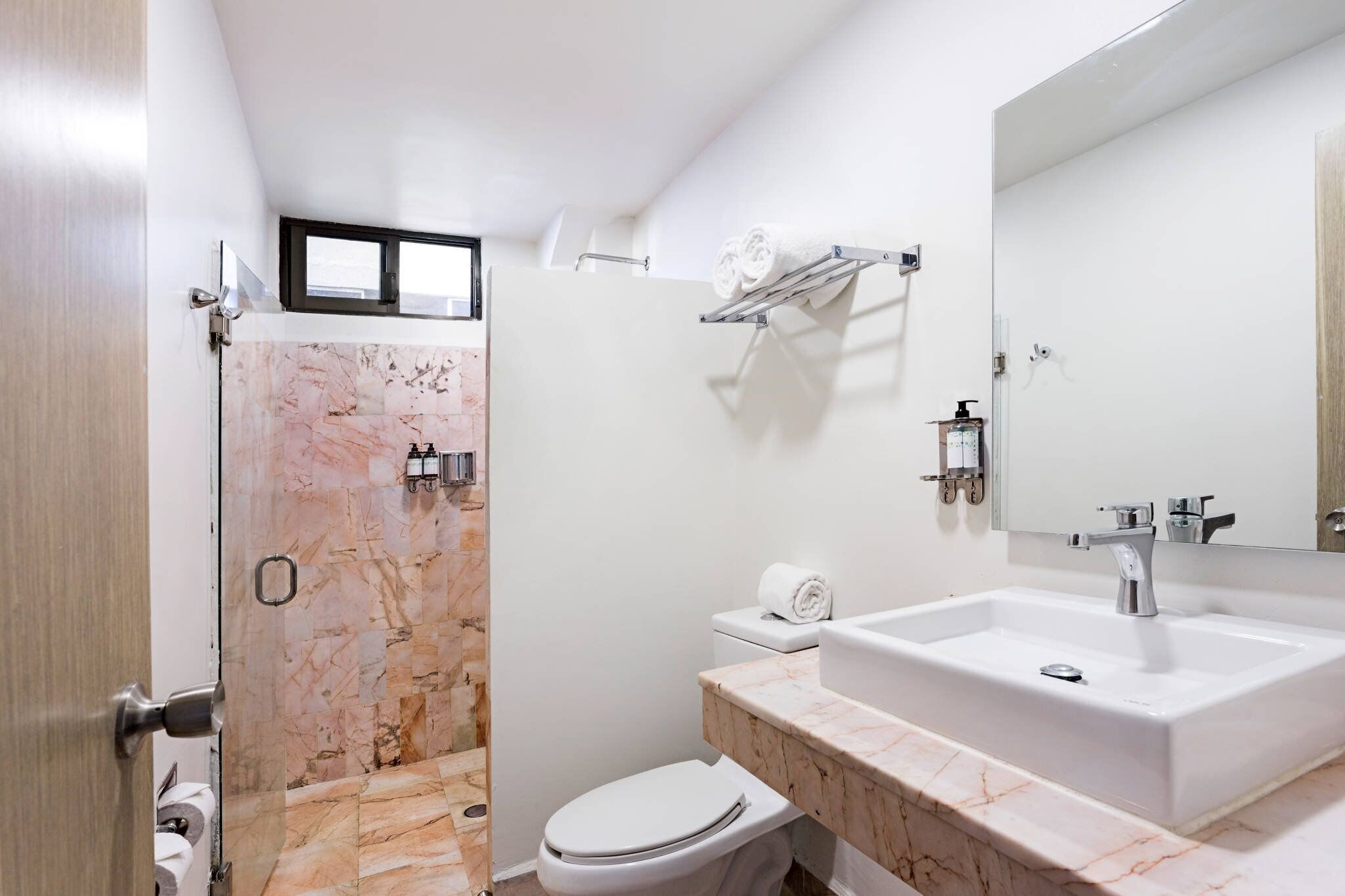 A modern bathroom with a marble shower, a white toilet, a sink with a mirror, and a towel rack.