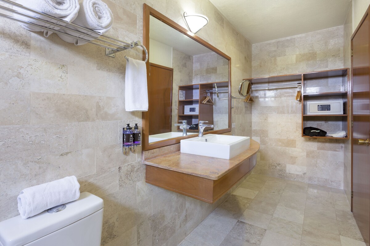 Un baño moderno con un espejo grande, un lavabo blanco y un perchero para toallas.