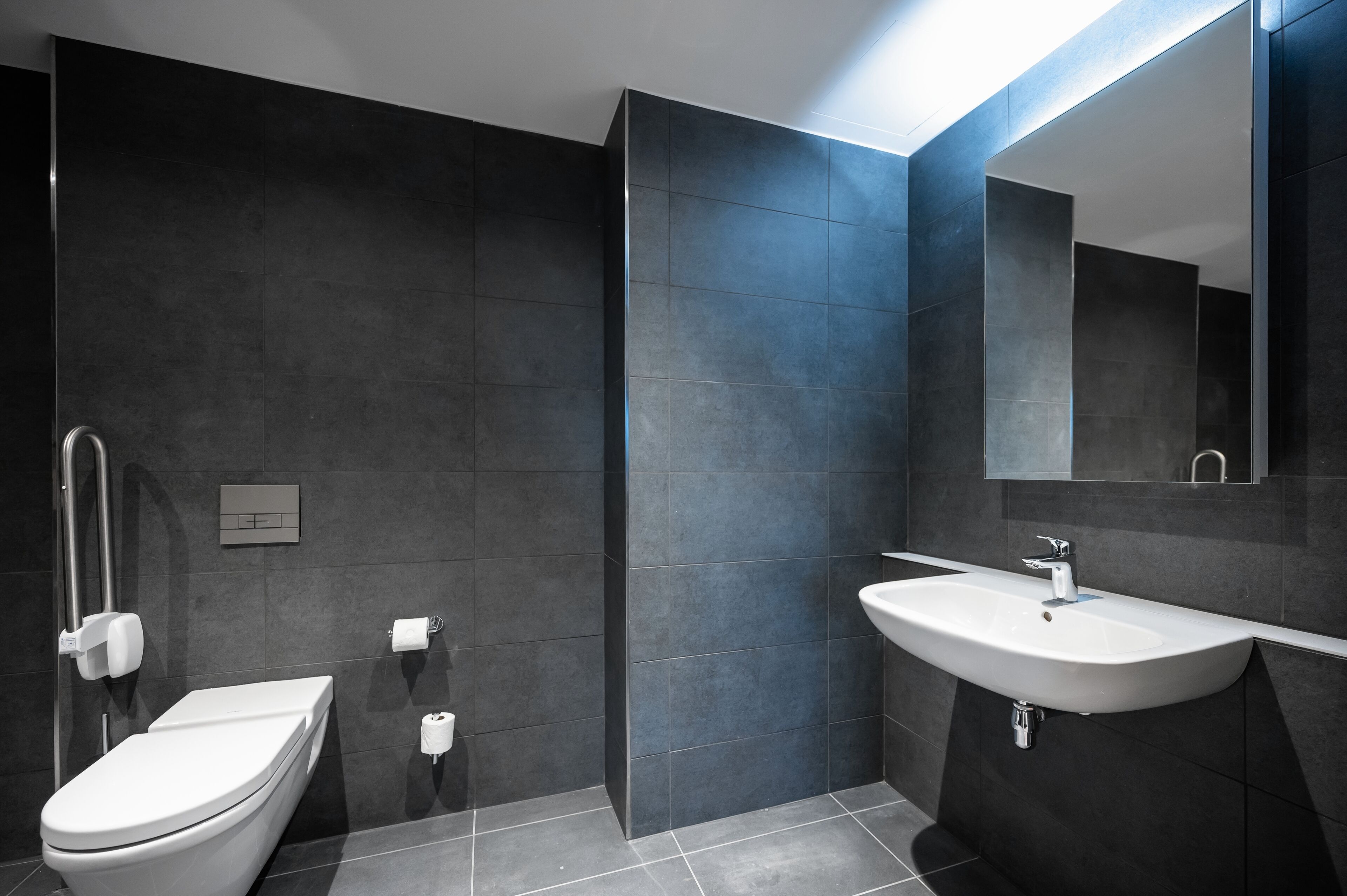Un baño moderno con inodoro, lavamanos y espejo.