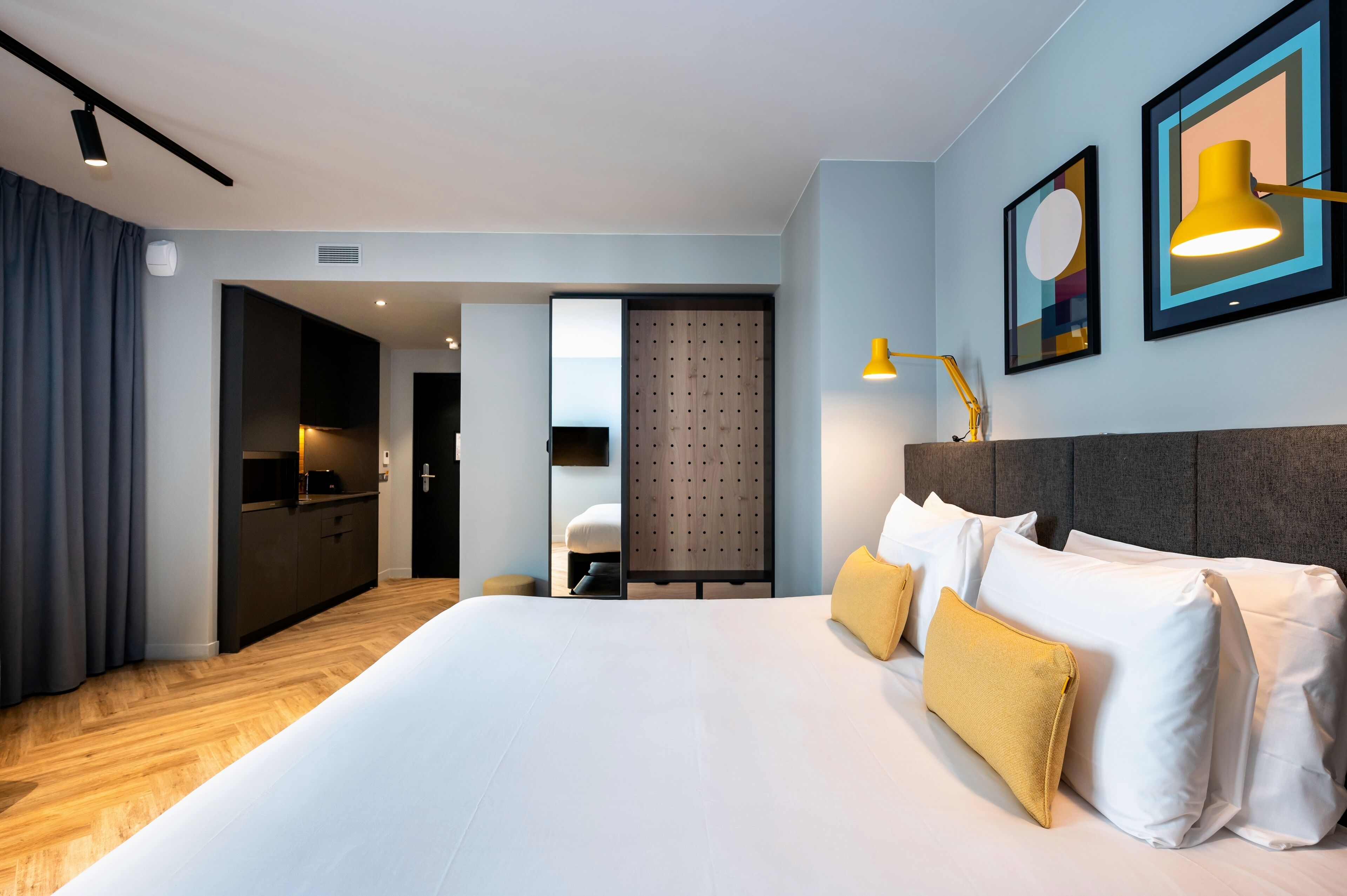 Een moderne hotelkamer met een groot bed, een bureau en een kitchenette.