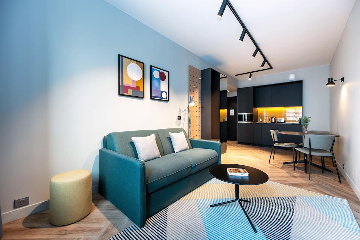 Un salon moderne avec un canapé, une table basse ronde et un coin repas avec des chaises.