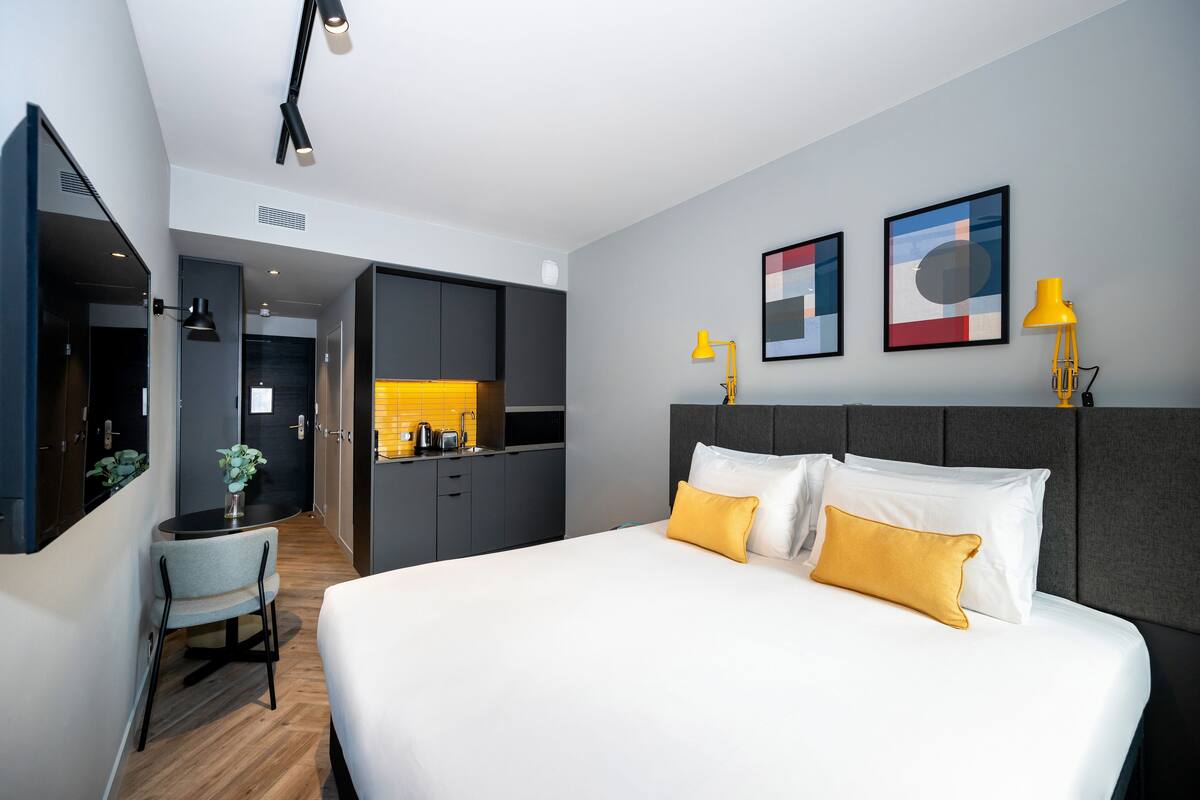 Une chambre d’hôtel moderne dotée d’un grand lit, d’un bureau et d’une kitchenette.