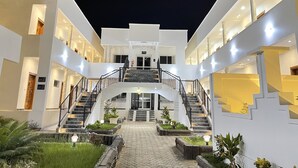 Um hotel com vários níveis, uma escadaria central e paisagismo externo.