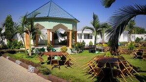 Um gazebo com telhado de azulejos, cercado por palmeiras e um gramado bem cuidado.