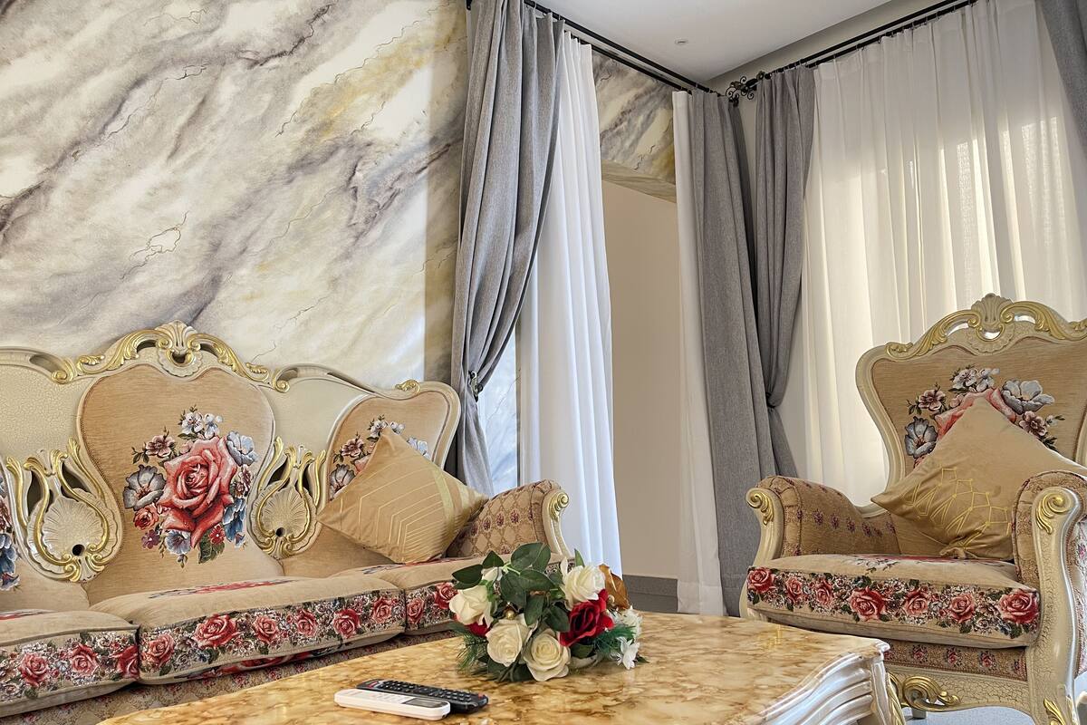 A luxurious room with a marble wall, a sofa set with floral upholstery, and a marble coffee table.
