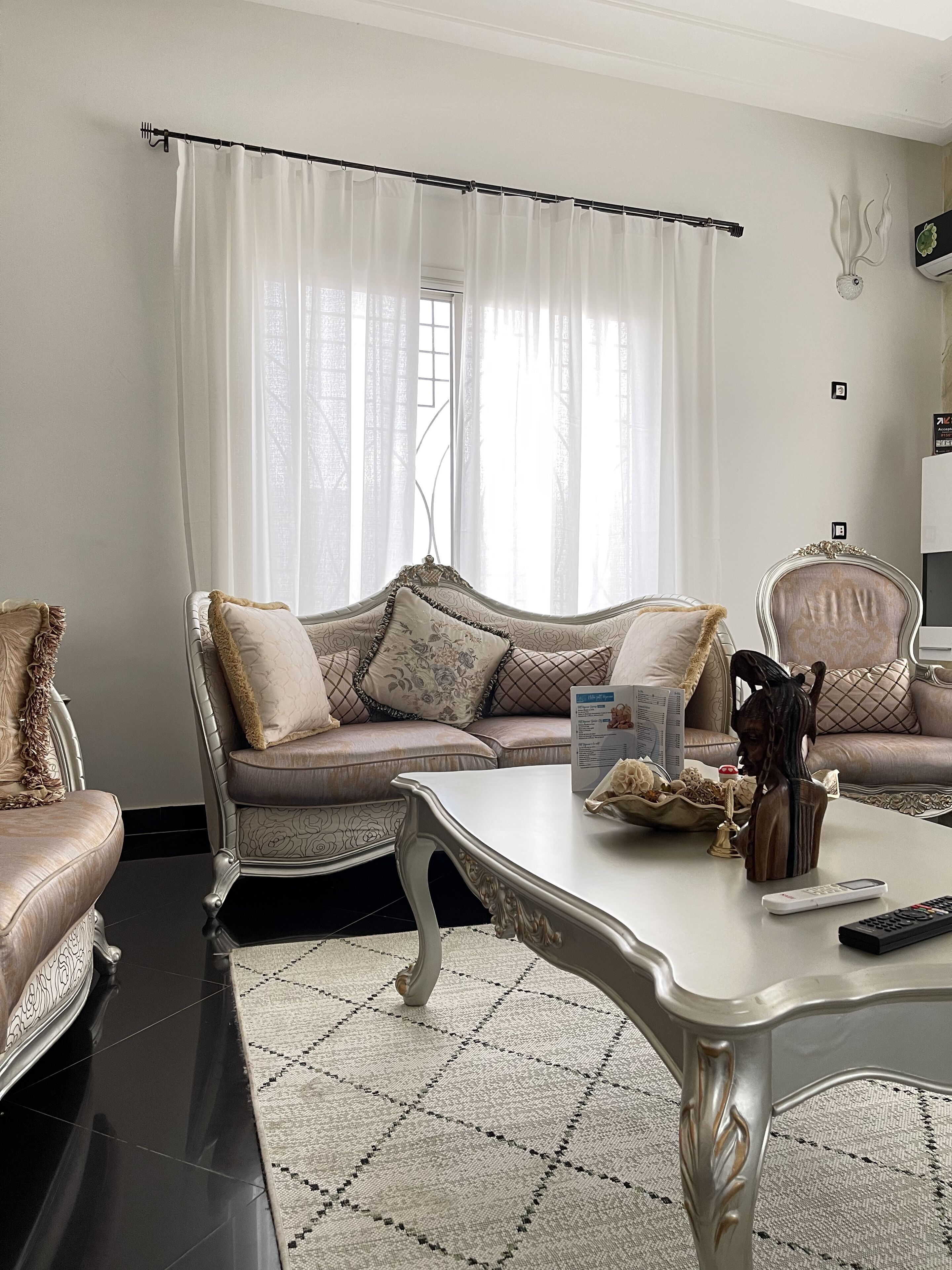 A living room with a sofa, armchairs, a coffee table, and a rug.