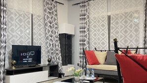 Uma sala de estar moderna com uma televisão de tela plana, um sofá, uma mesa de centro e cortinas estampadas.