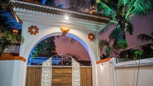 A gated entrance with a decorative archway, a wooden door, and a metal gate with intricate designs. - Casa Albuquerque (Vagator)