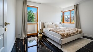 A bedroom with a bed, two windows, a door, and a modern light fixture. - Serenity Prague Villa with garden jacuzzi (Pruhonice)
