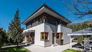 A modern two-story house with a covered patio and a well-maintained lawn. - Serenity Prague Villa with garden jacuzzi (Pruhonice)