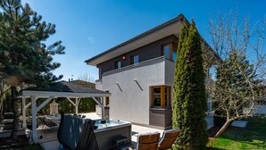 A modern two-story house with a covered patio, outdoor seating, and a hot tub. - Serenity Prague Villa with garden jacuzzi (Pruhonice)