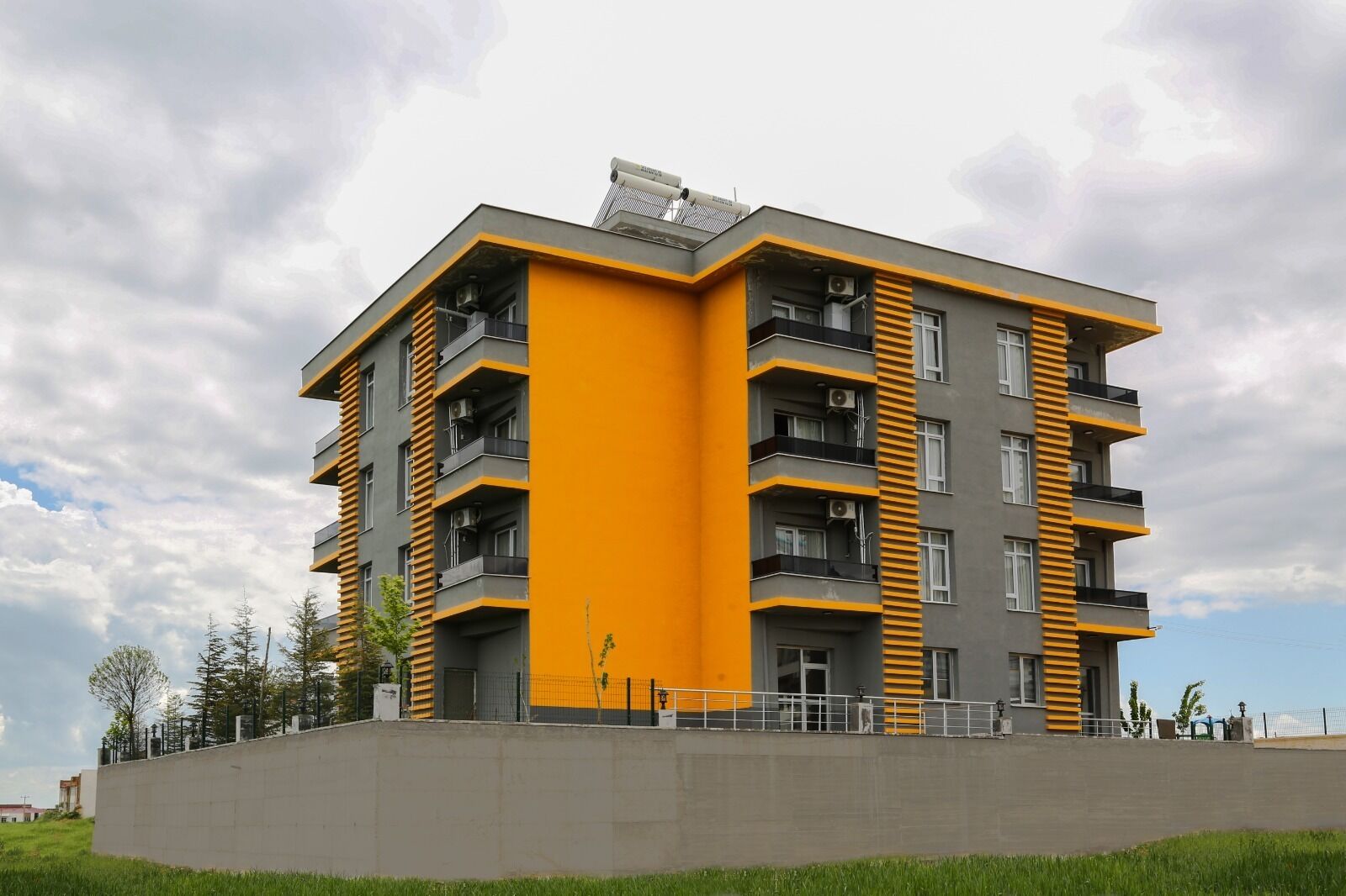 A multi-story residential building with balconies, a flat roof, and a concrete base.