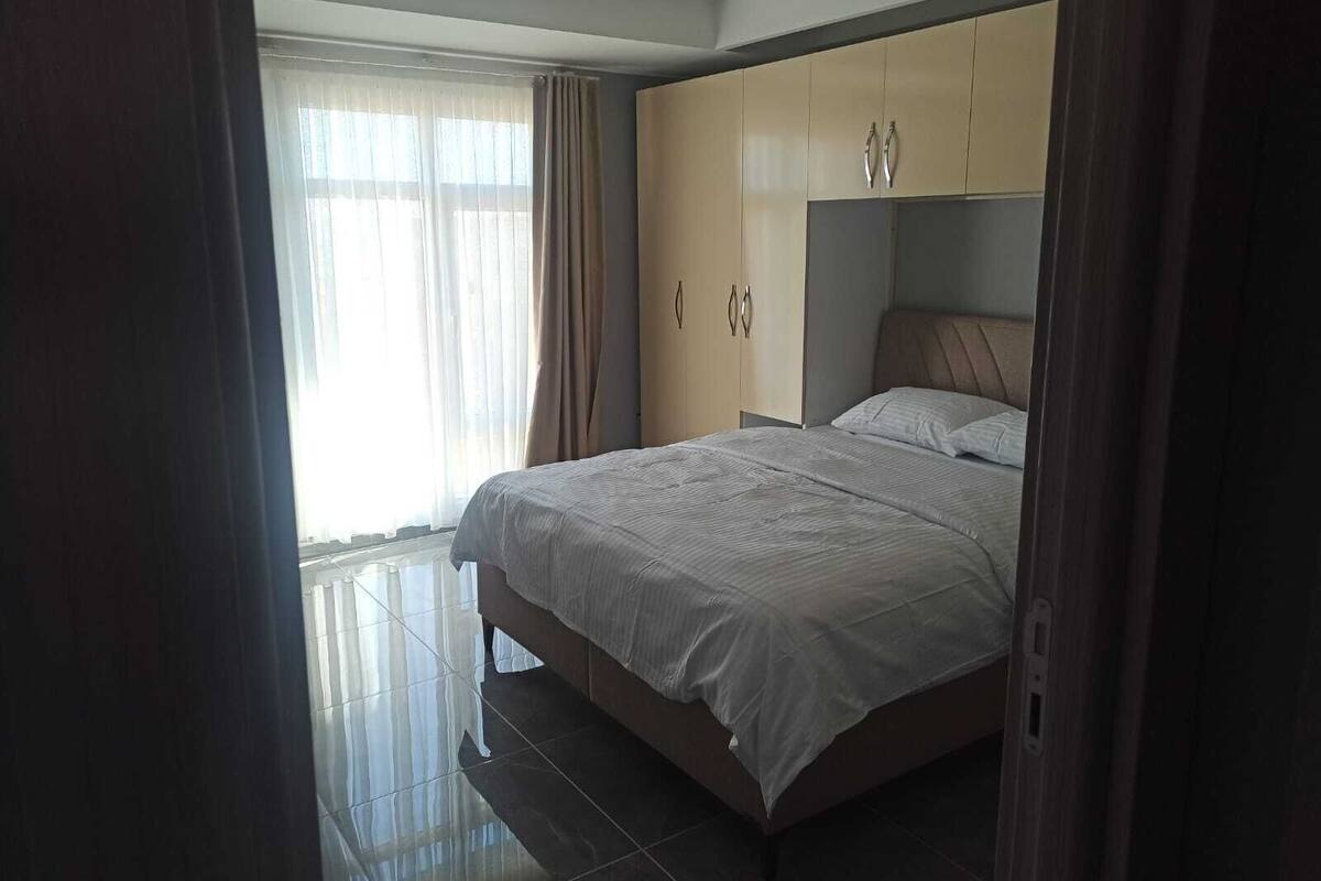 A bedroom with a bed, a wardrobe, and a window with curtains.