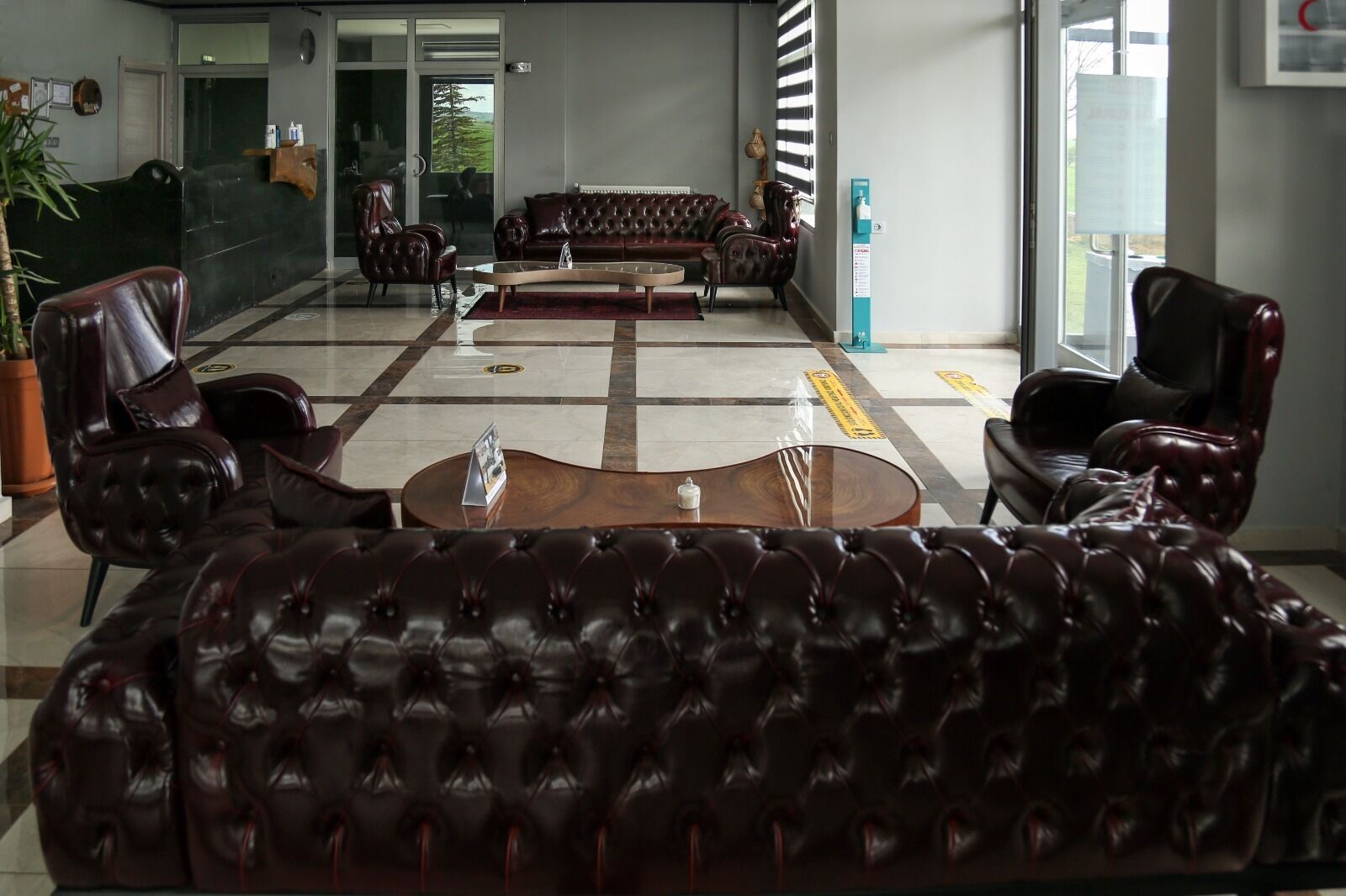 Um lobby amplo com sofás de couro, uma mesa de centro e um balcão de recepção.