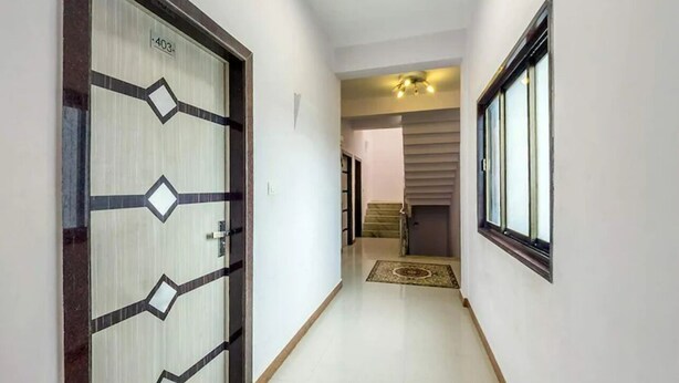 Un pasillo con una puerta estampada, una ventana y una escalera que conduce a otra habitación.
