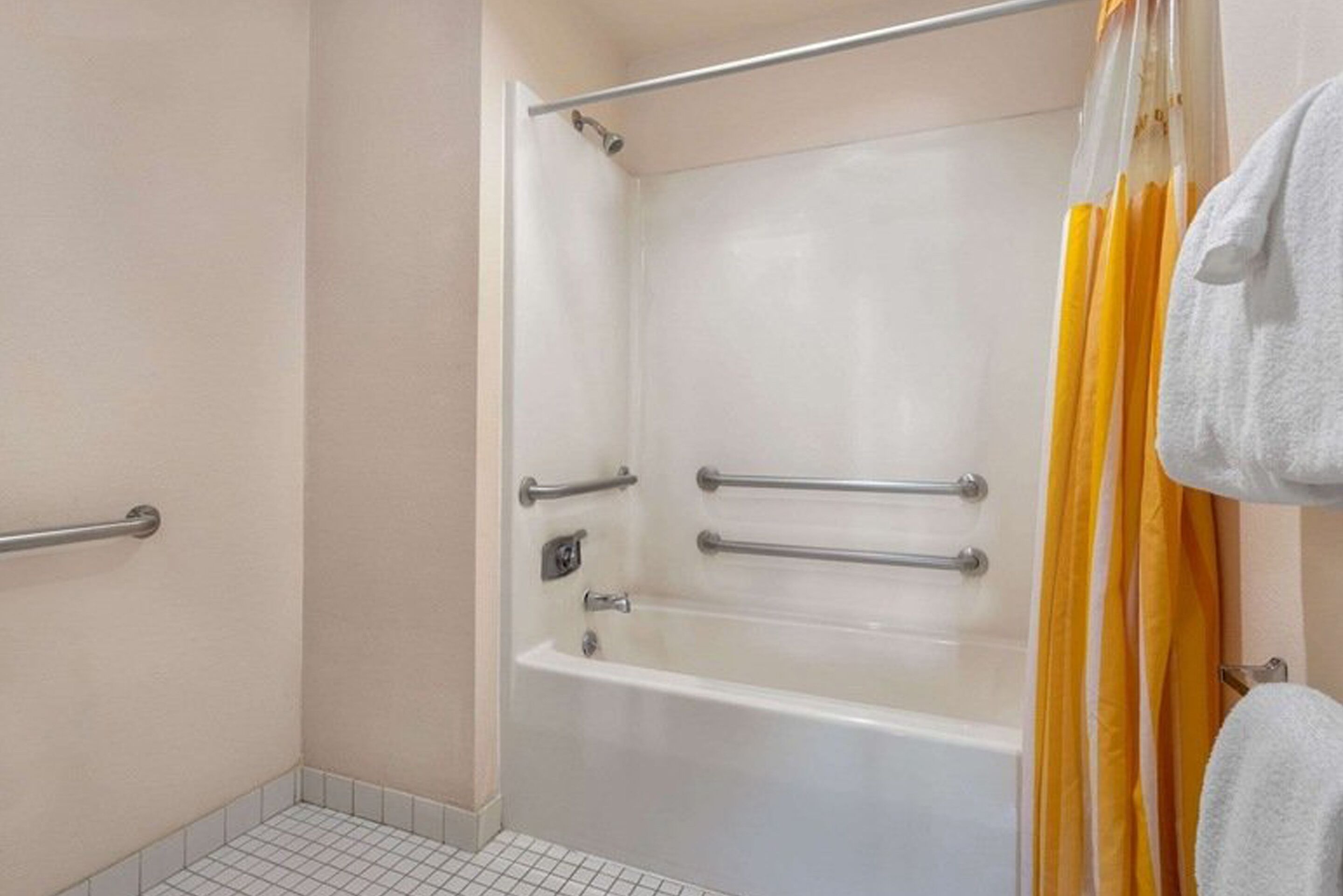 A bathroom with a bathtub, grab bars, and a shower curtain.