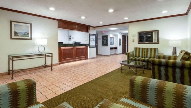 A lobby with a reception desk, a sofa, a coffee table, and a patterned rug. - Norwood Inn & Suites by BlissPoint Post Rd Indianapolis (Indianapolis)
