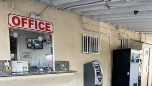 An office with a 'No Visitors' sign, an ATM, and a security camera. - American Inn (Perris)