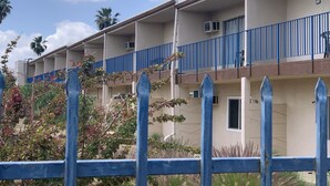 A multi-story building with balconies, air conditioning units, and a blue railing. - American Inn (Perris)