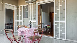 An outdoor dining area with a table set for two, a bottle of wine, and a chair. - GuestHost - Roomy and tastefully furnished apartment, ideal for families as it accommodates up to 6 people having 2 bedrooms, 2 bathrooms, a balcony and an equipped terrace. The flat is located in a residential context with concierge and internal garden, (Bari)