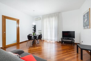 Un salon moderne avec un canapé, une table à manger et des chaises, un téléviseur et un tableau accroché au mur.