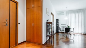 A room with wooden flooring, a dining table with chairs, a cabinet, and a radiator. - GuestHost - Roomy and tastefully furnished apartment, ideal for families as it accommodates up to 6 people having 2 bedrooms, 2 bathrooms, a balcony and an equipped terrace. The flat is located in a residential context with concierge and internal garden, (Bari)