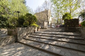 A stone staircase leading up to a building, surrounded by trees and greenery.