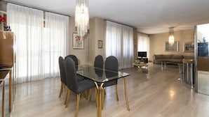 Un salon moderne avec une table à manger en verre, des chaises foncées, un canapé et un téléviseur.