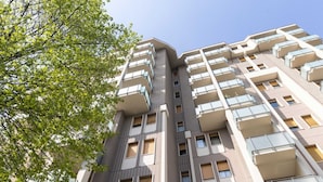 Un immeuble résidentiel à plusieurs étages, doté de balcons, de grandes fenêtres et d’un arbre au premier plan.